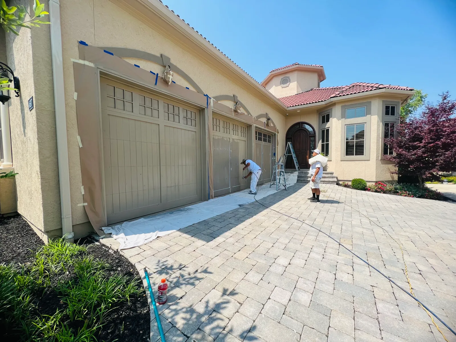 Garage doors being painted on stucco home